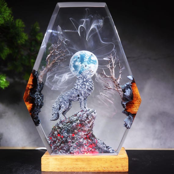 A handcrafted resin diorama lamp where a howling wolf silhouette is frozen mid-howl under a glowing full moon inside a coffin-shaped epoxy block — genuinely eerie and one-of-a-kind.