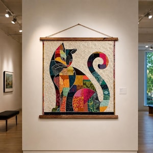 May include: A square wall hanging featuring a patchwork cat silhouette composed of various colorful fabric patterns. The cat is set against a cream-colored background with intricate swirling quilted textures, suspended from a wooden frame.