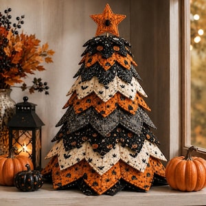 May include: A decorative fabric tree constructed from layered, quilted fabric petals in black, orange, and cream colors. The fabric features patterns of pumpkins, bats, and spiderwebs. An orange star with a black spider sits at the top of the tree.