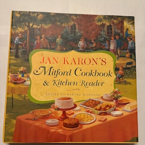 May include: A cookbook titled "Jan Karon's Mitford Cookbook & Kitchen Reader" with a colorful illustration of a gathering. The cover features a table laden with food, and a background scene of people outdoors. Edited by Martha McIntosh.