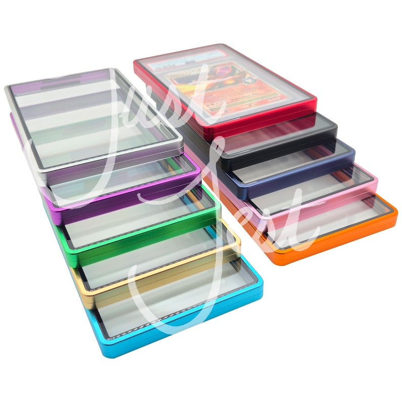 May include: A collection of colorful card cases with clear tops. The cases are in various colors, including red, black, blue, pink, orange, green, purple, and silver. One case contains a trading card. The cases are stacked and arranged.