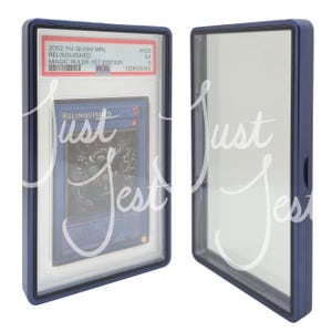 May include: Two blue card display cases. One case contains a Yu-Gi-Oh! card labeled "RELINQUISHED" with the text "MAGIC RULER-1ST EDITION". The other case is empty. The cases are rectangular with a clear front.