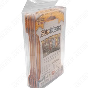 May include: A clear plastic display case containing multiple packs of Pok&eacute;mon Sun & Moon trading cards. The packaging features the Pok&eacute;mon logo and card pack graphics. The case is designed to protect and showcase the cards.