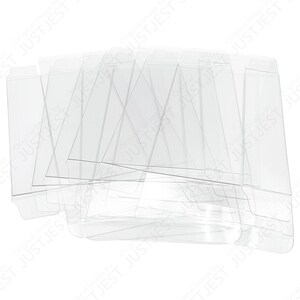 May include: A stack of clear, unfolded, transparent plastic boxes, likely for packaging small items. The boxes are rectangular with fold lines and tabs, and are arranged against a white background.