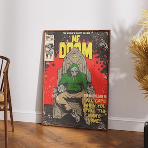以下が含まれることがあります： MF DOOMが玉座に座っている額入りのコミックアート。アートワークは赤い背景に「MF DOOM」の文字が大きな黄色で書かれています。「THE WORLD'S ILLEST VILLAIN」の文字が上部にあります。