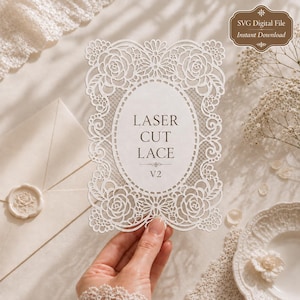 May include: A white rectangular card featuring an intricate laser-cut lace border with floral rose motifs and a central oval frame. The text LASER CUT LACE V2 is printed in the center. The card is held against a light background with lace.