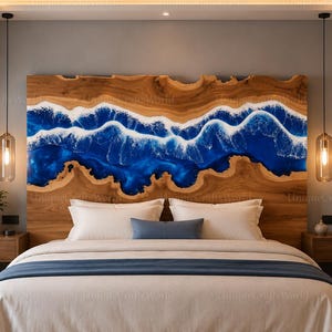 May include: A large rectangular headboard made of natural wood with a live edge, featuring a central horizontal inlay of deep blue resin that mimics the appearance of ocean waves with white foam detailing, positioned behind a bed with white bedding.