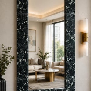May include: A rectangular wall mirror featuring a dark green and black marble-patterned frame with white veining. The mirror surface reflects a living room interior, and the frame has a smooth, polished finish with clean, straight edges.