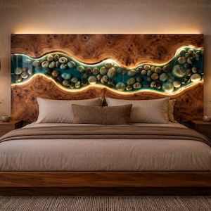 May include: A wooden headboard featuring a horizontal, wavy river-like inlay filled with smooth river stones and translucent blue resin. The inlay is backlit with warm LED lighting, contrasting against the natural wood grain of the headboard.
