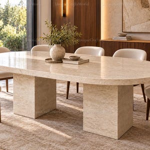 Peut inclure: Une table à manger ovale avec une surface en pierre beige polie et deux pieds rectangulaires assortis. La table est entourée de six chaises dotées d'assises rembourrées couleur crème et de dossiers incurvés avec des pieds en bois foncé.