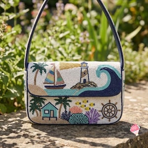 May include: A rectangular shoulder bag featuring intricate beadwork depicting a coastal scene with a sailboat, a lighthouse, a large blue wave, palm trees, a small house, coral, and a ship's wheel on a white background with a dark blue strap.