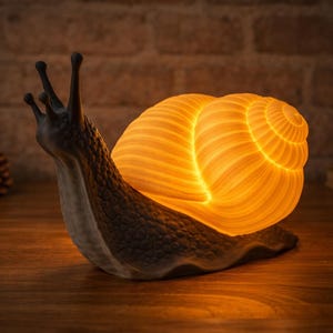 May include: A whimsical snail-shaped lamp with a glowing, spiraled shell. The lamp's shell emits a warm, orange light, contrasting with the dark gray body. The lamp is a decorative accent piece, perfect for a bedside table or shelf.