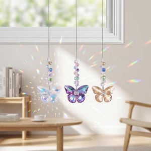 May include: Three hanging suncatchers featuring faceted crystal butterflies in clear, purple, and amber tones. Each butterfly is suspended from a silver-toned chain adorned with a vertical strand of multi-colored, spherical crystal beads that refract light.