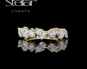 May include: A gold band ring with a series of diamonds in various shapes, including round and pear-cut stones. The ring is set against a black background with the text "Stellar Carats" in the upper left corner.