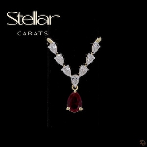 May include: A V-shaped necklace featuring a central pear-cut deep red gemstone suspended from a gold chain adorned with seven pear-cut clear white stones arranged in a symmetrical pattern. The text Stellar CARATS is visible at the top left.