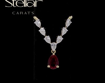 May include: A V-shaped necklace featuring a central pear-cut deep red gemstone suspended from a gold chain adorned with seven pear-cut clear white stones arranged in a symmetrical pattern. The text Stellar CARATS is visible at the top left.