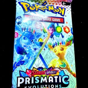 May include: A sealed Pokémon Trading Card Game pack. The pack features the Pokémon logo and the text "Scarlet & Violet Prismatic Evolutions". The packaging is primarily light blue with images of Pokémon characters and colourful geometric shapes.