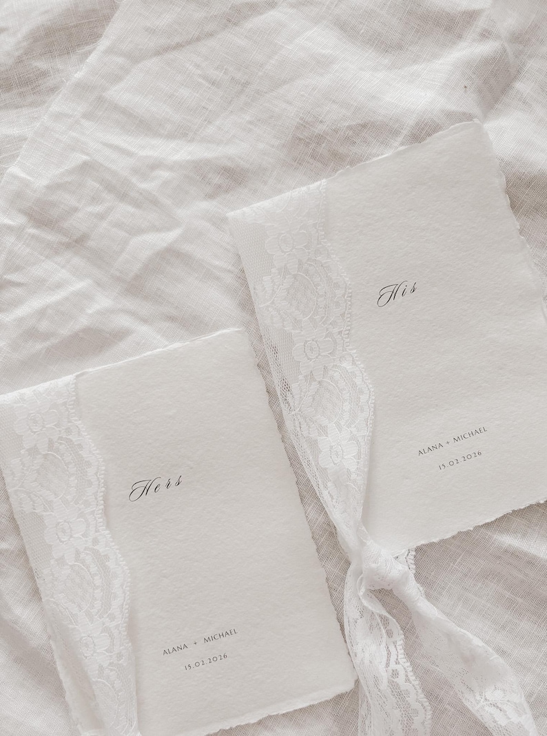 May include: Two white wedding programs with lace trim and the words "Hers" and "His" in elegant script. The programs are tied together with a white ribbon. The names "Alana + Michael" and the date "15.01.2026" are printed on the programs.