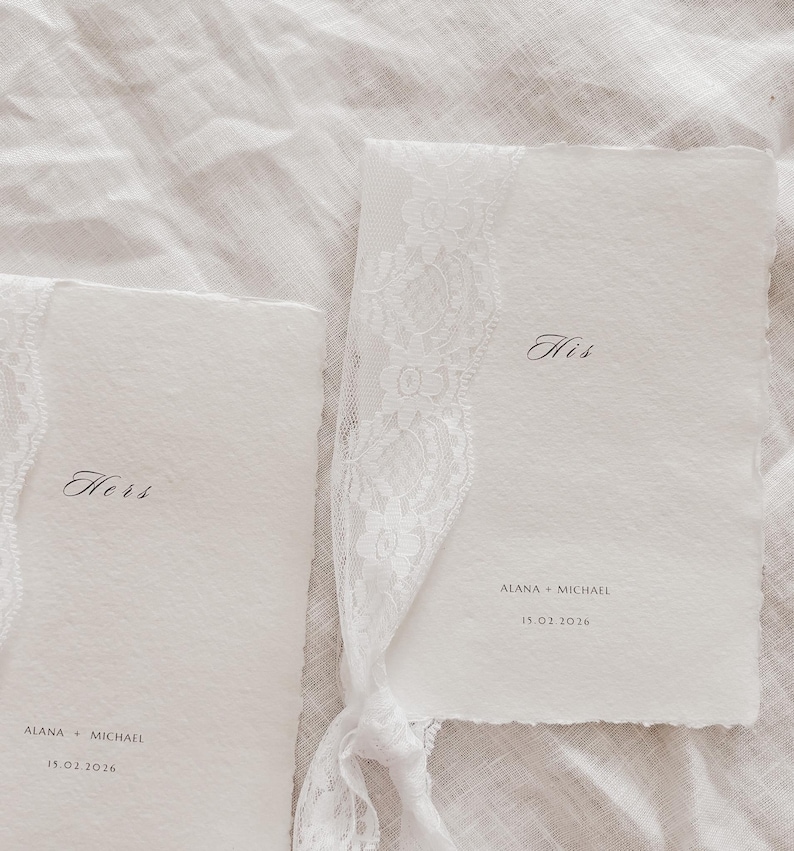 May include: Two white wedding programs with the words "Hers" and "His" in elegant script. The programs are adorned with delicate white lace and tied together. The names "Alana + Michael" and the date "15.02.2016" are printed on the programs.