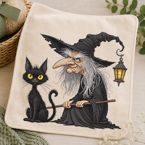 Könnte beinhalten: Ein quadratischer, cremefarbener Stoffartikel mit einer aufgedruckten Illustration einer Hexe mit langem grauem Haar, spitzem Hut und Hakennase, die einen Holzstab hält. Eine schwarze Katze mit gelben Augen sitzt daneben, eine Laterne hängt am Hut.