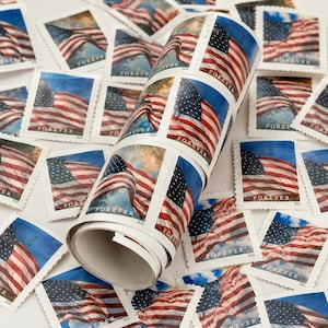 May include: A roll of "Forever" postage stamps featuring the American flag waving in the wind against a blue sky. Individual stamps are scattered around the roll, showcasing the same design. The stamps are marked with "USA" and the year "2024".