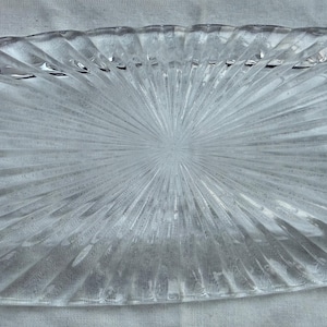 May include: A white ceramic mug with a black handle and the text "But First, Coffee" in a bold, black font. The mug is set against a blurred background, suggesting a cozy setting.