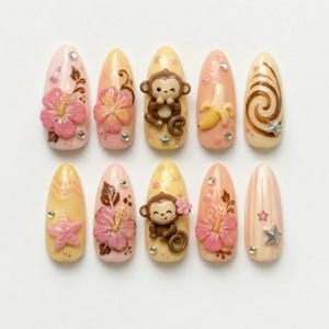 Könnte beinhalten: Ein Set aus zehn mandelförmigen Kunstnägeln mit tropischem Thema. Jeder Nagel hat ein anderes Design, darunter rosa Hibiskusblüten, ein zwinkernder Affe, eine Banane und Sternakzente. Die Nägel sind in Rosa-, Gelb- und Brauntönen lackiert.