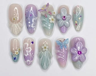Uñas postizas con estampado floral en tonos pastel, manicura con mariposas 3D estilo jardín de hadas.