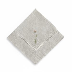 May include: A square, pale grey linen napkin featuring an embroidered flower design. The flower is a soft pink with green leaves and stem. The napkin has a white, cut-out border along one edge.