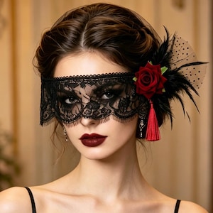 May include: Black lace masquerade mask with a floral and feather accent. The mask features a delicate lace design, a red rose, black feathers, and a red tassel. The mask is designed for a formal event or costume.