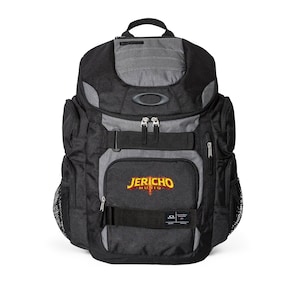 Puede incluir: Mochila negra y gris con el texto "Jericho Music" en amarillo y rojo. La mochila tiene múltiples compartimentos, un asa superior y bolsillos laterales de malla. El logotipo de Oakley es visible.