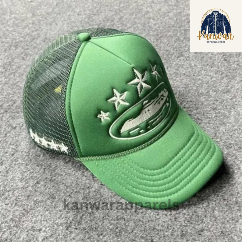Puede incluir: Gorra de camionero verde con la parte trasera de malla y visera curva. El panel frontal presenta un dise&ntilde;o bordado blanco de un cocodrilo y estrellas. El sombrero tiene el texto "kanwarapparels" en la visera.