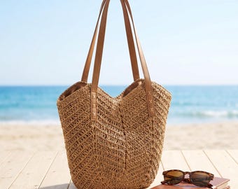 Puede incluir: Un bolso tote de paja trenzada color canela con largas correas marrones para el hombro y un patrón de chevrón. Junto al bolso hay un cuaderno marrón cerrado con un par de gafas de sol de montura oscura sobre la cubierta, de tejido abierto.