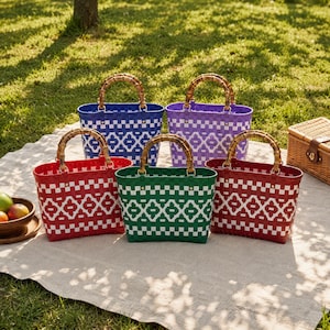 May include: Five woven plastic tote bags with bamboo handles arranged in a group. The bags feature a repeating white geometric pattern against solid colors of blue, purple, red, green, and a second red. Each bag has a rectangular base.