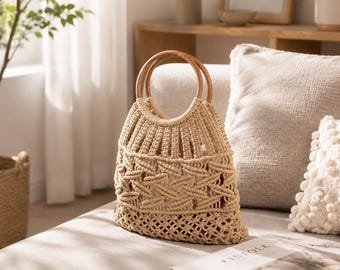 May include: A beige macrame tote bag with wooden handles. The bag features a geometric pattern and a red lining. The bag is sitting on a light-colored sofa. The bag is a stylish accessory for carrying items.