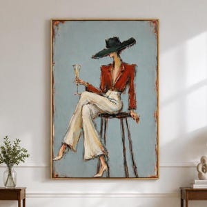 Op de afbeelding: Een ingelijste kunstdruk met een olieverfschilderij van een figuur met een zwarte hoed met brede rand, een rode blazer en een lichte broek, zittend op een kruk met een glas op een steel tegen een gedempte blauwe achtergrond.