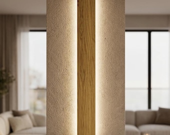 May include: A vertical rectangular wall light fixture made of light-toned wood with a prominent grain pattern. The fixture is mounted on a textured wall and emits a soft, warm glow from behind its edges, creating a halo effect against the surface.