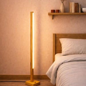 May include: A tall, slender floor lamp constructed from light-toned wood with a vertical, integrated LED light strip running along its length. The lamp features a square wooden base and emits a warm, soft glow, standing upright on a wooden floor.