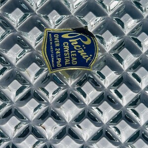 May include: Close-up of a clear lead crystal glass with a diamond pattern. A blue and yellow label reads "Phoenix Lead Crystal Over 24% PbO Made in West Germany."