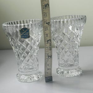 May include: Two clear lead crystal vases with a diamond pattern, each approximately 4 inches tall. A measuring tape is placed next to the vases. One vase has a blue and white label that reads "Phoenix Lead Crystal Over 24% PbO".