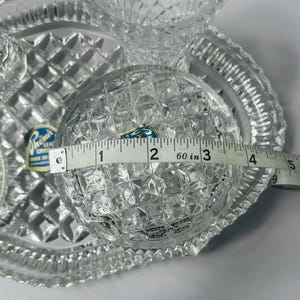 May include: Clear crystal serving set with diamond-cut pattern. The round bowl measures approximately 3 inches in diameter. Includes a serving tray and two smaller bowls. The set has a Phoenix Crystal label.