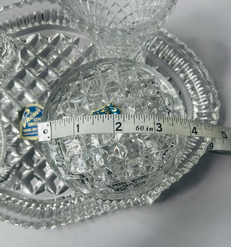 May include: Clear crystal serving set with diamond-cut pattern. The round bowl measures approximately 3 inches in diameter. Includes a serving tray and two smaller bowls. The set has a Phoenix Crystal label.
