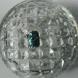 May include: Clear lead crystal bowl with a diamond pattern. The bowl has a rounded shape and a textured surface. A blue and gold label is affixed to the bowl, indicating it is lead crystal.