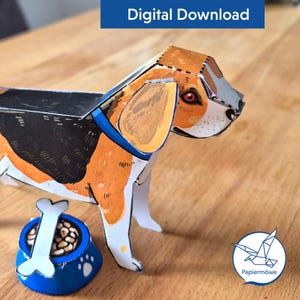 May include: A papercraft beagle dog with orange, black, and white markings, wearing a blue collar. A blue bowl with a bone and food is next to the dog. The words "Digital Download" are in a blue rectangle at the top.