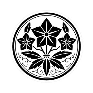 May include: A black and white circular emblem featuring three five-pointed star-shaped flowers, leaves, and decorative swirls. The design is enclosed within a black circular border.