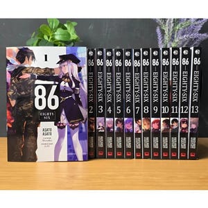 Puede incluir: Una colección de trece libros manga "86 EIGHTY-SIX". El primer volumen presenta una ilustración a color de dos personajes. Las lomos de los otros libros son negros con texto blanco. Los libros están dispuestos en fila.