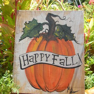May include: A wooden sign with a painted pumpkin and the words "Happy Fall" in a white banner. The pumpkin is orange with green leaves and a brown stem.