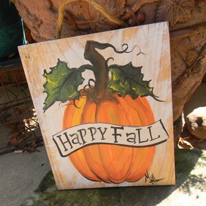 May include: A wooden sign with a painted pumpkin and the words "Happy Fall" in black script. The pumpkin is orange with green leaves and a brown stem.