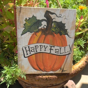 May include: A wooden sign with a painted orange pumpkin and green leaves. The sign says "Happy Fall" in a white banner.