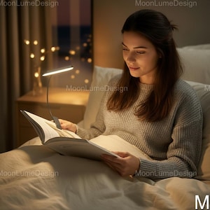May include: A woman reading in bed under the soft glow of a flexible LED book light. The light is attached to the book, illuminating the pages. The scene is warm and inviting, with a cozy atmosphere.
